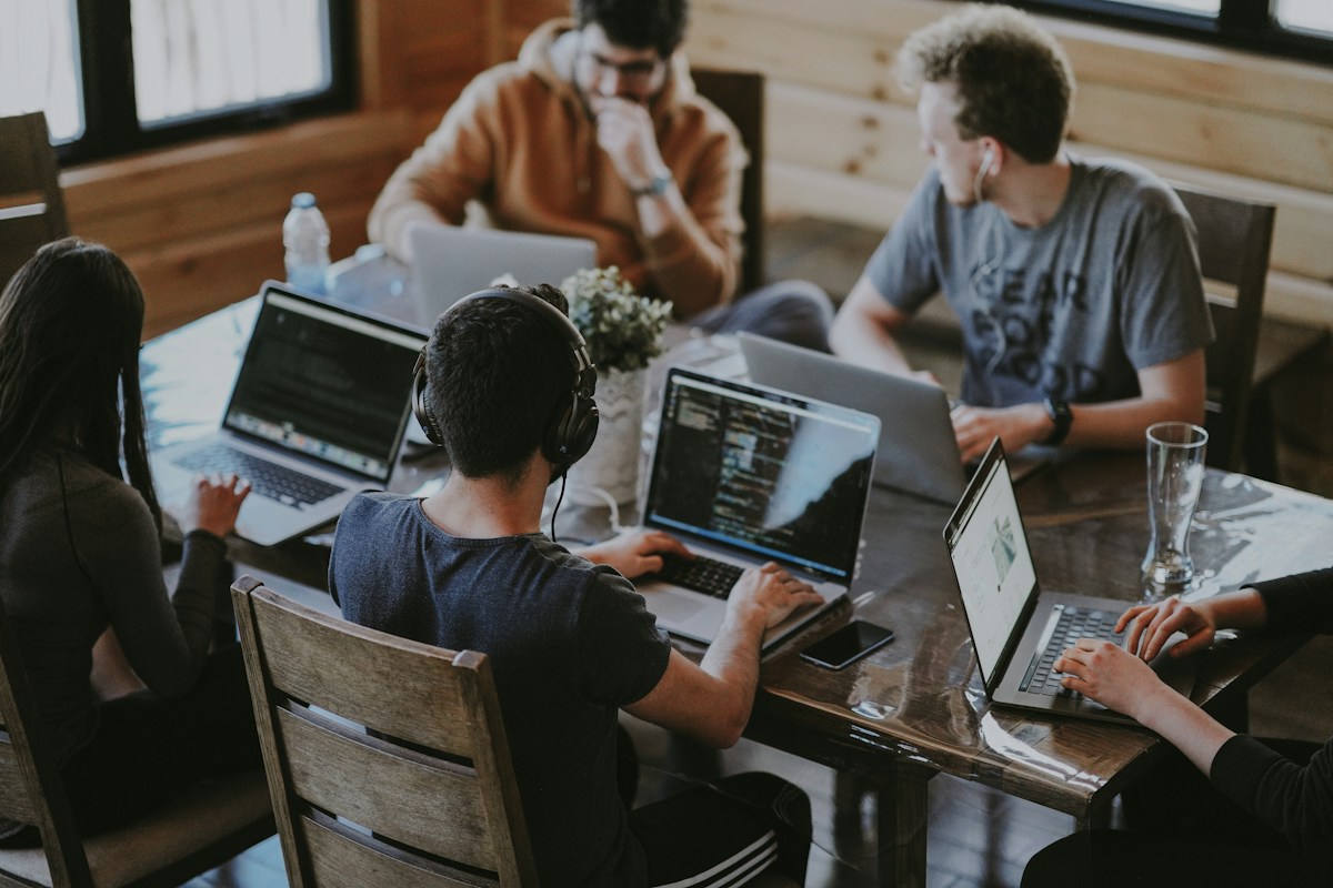 A small team collaborating around a table with laptops
